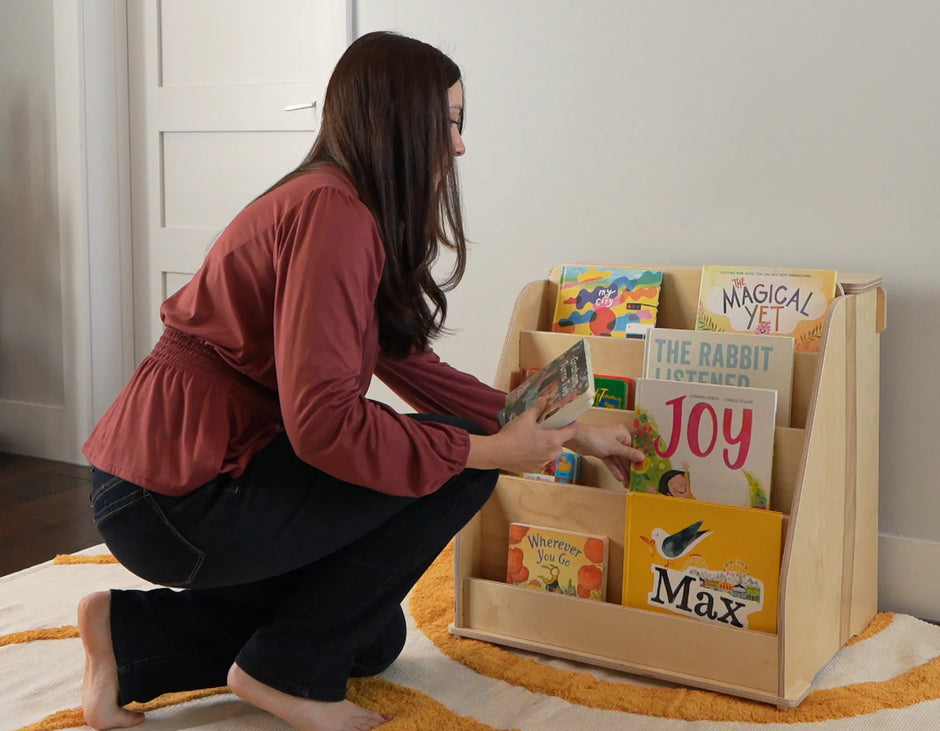 mom doing a book rotation on a montessori bookshelf