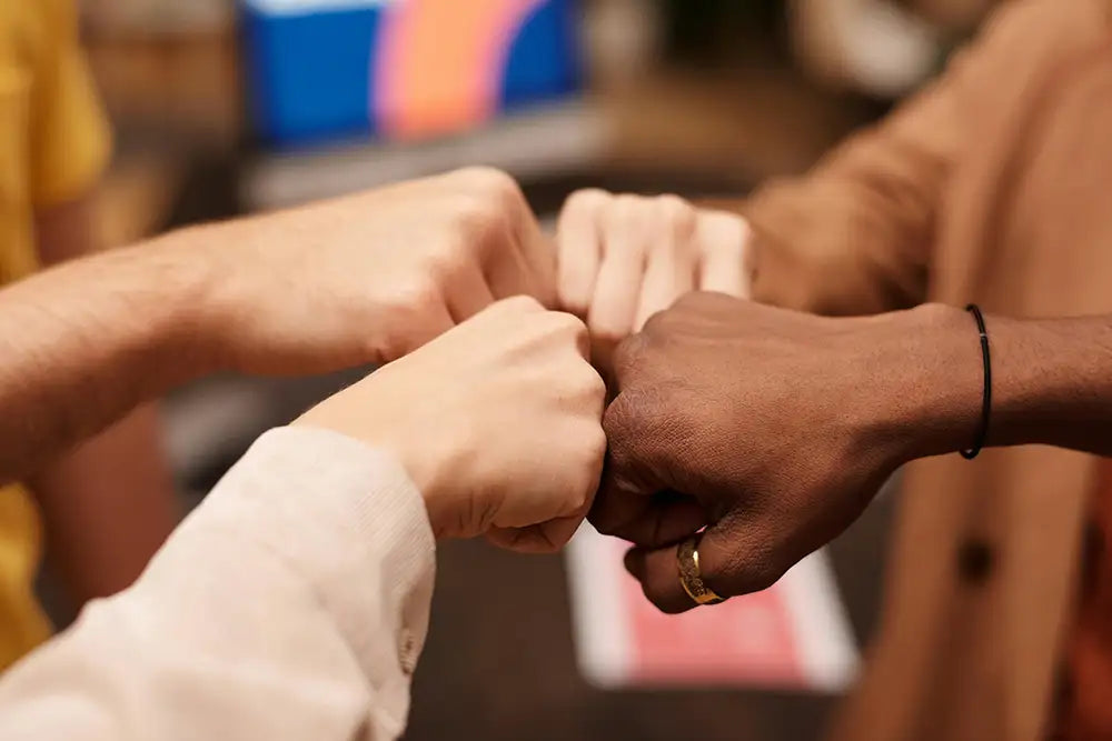 fist bumping 4 people, shows teamwork