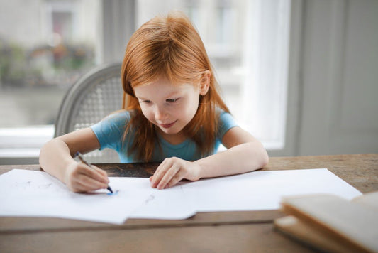 a girl drawing on a piece of paper