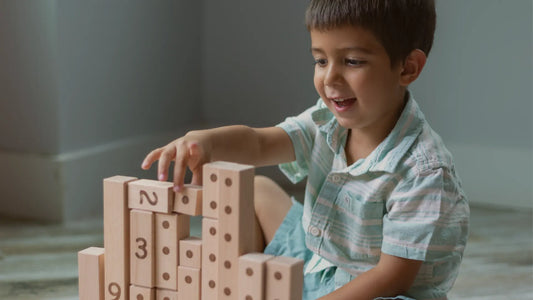Little boy stacking Montessori wooden blocks with number and dot engravings