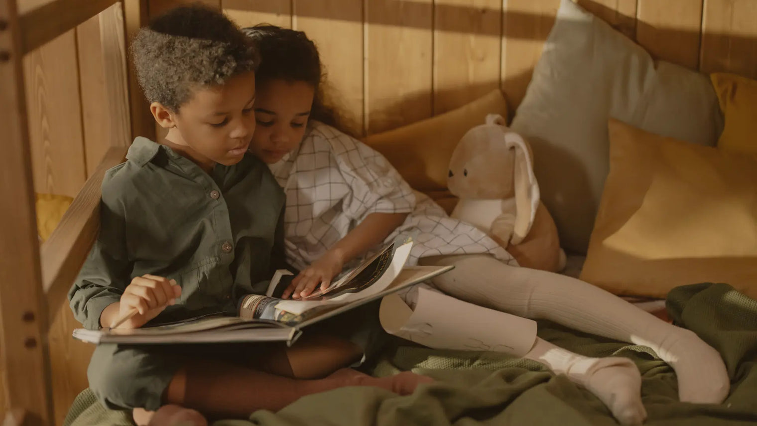 Two kids reading a book together in a cozy reading nook