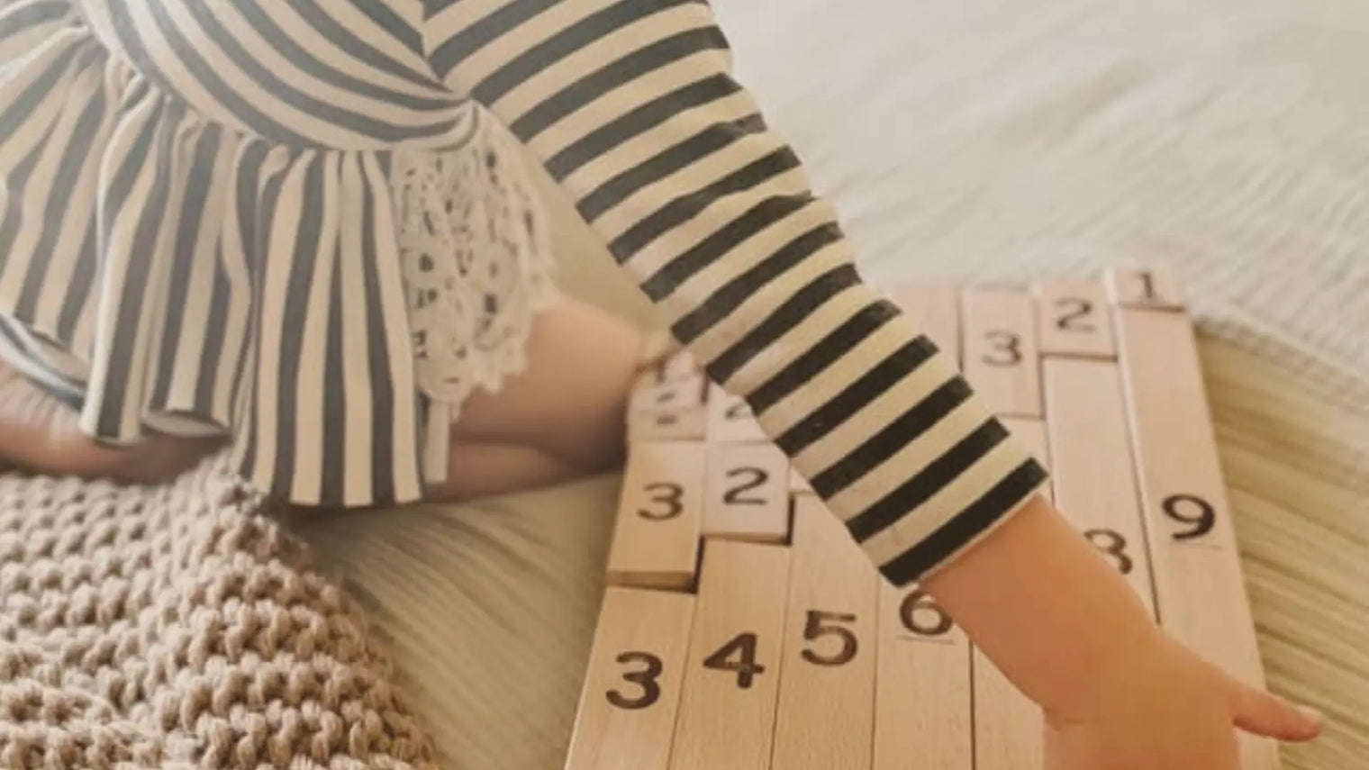 Little girl playing with Montessori Number Blocks on a bed