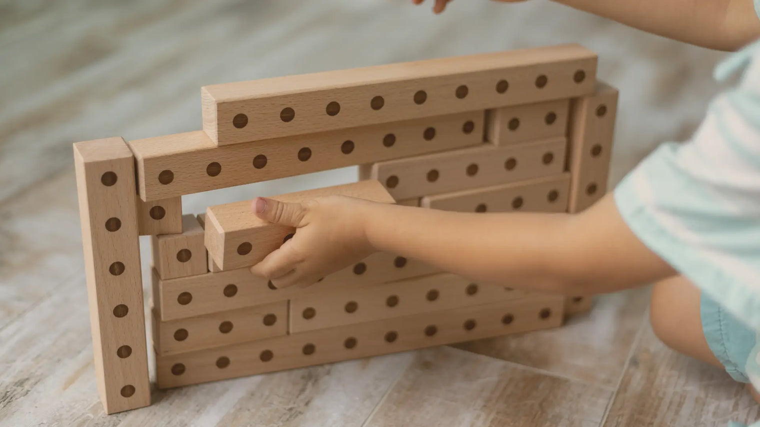 Little boy playing with Montessori wooden building blocks showcasing engraved details for tactile learning