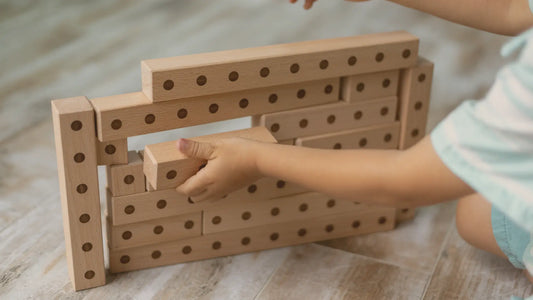 Little boy playing with Montessori wooden building blocks showcasing engraved details for tactile learning