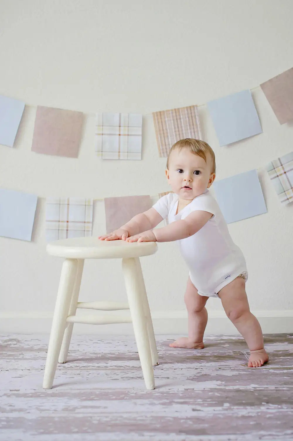 little baby standing up on her own feet using a chair