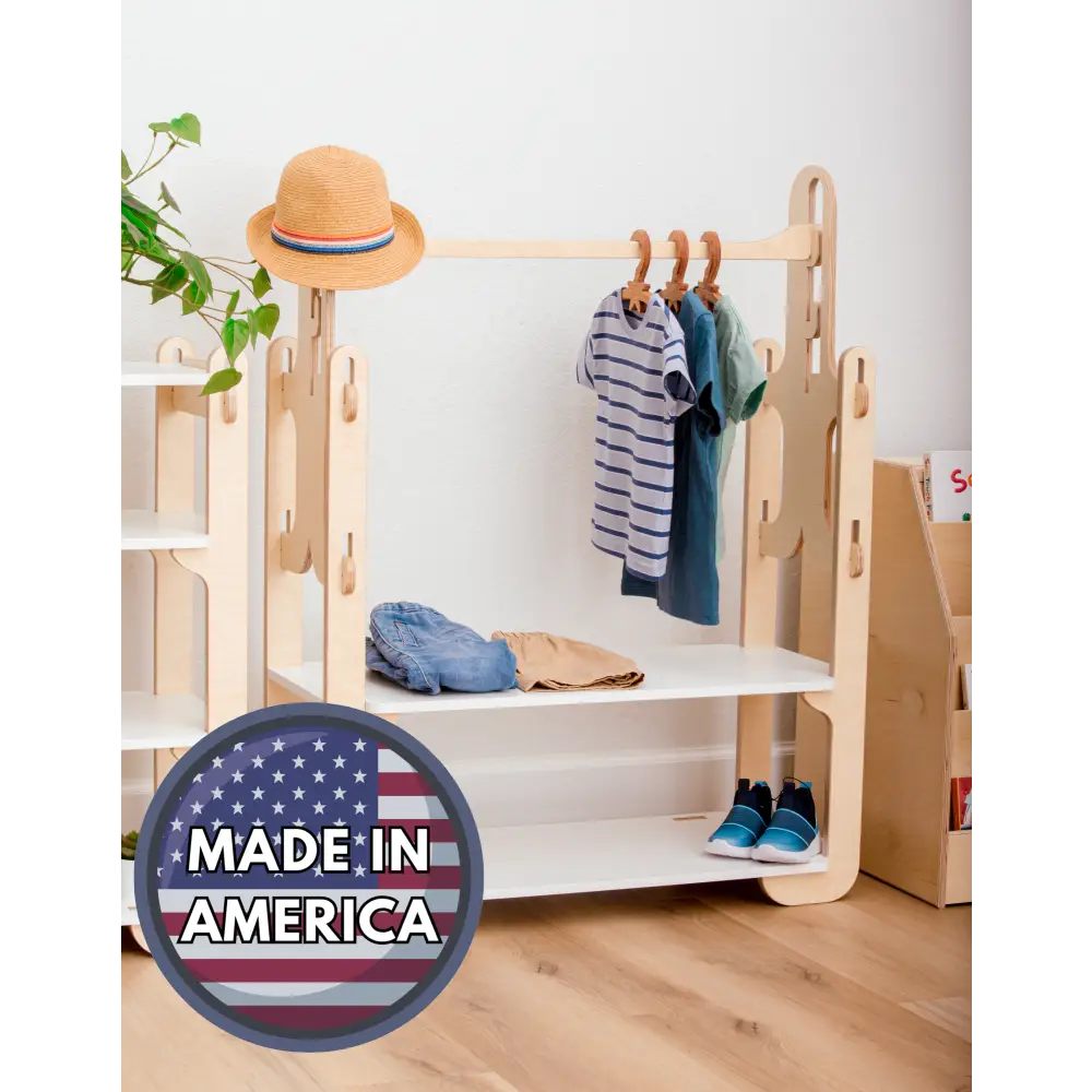 Made in America wooden clothing rack, featuring a stylish straw hat, a blue and white striped shirt, a teal tunic, casual denim jeans, and trendy blue sneakers. Perfectly blending form and function for kids' room organization, this rack showcases sustainable craftsmanship and support for American manufacturing