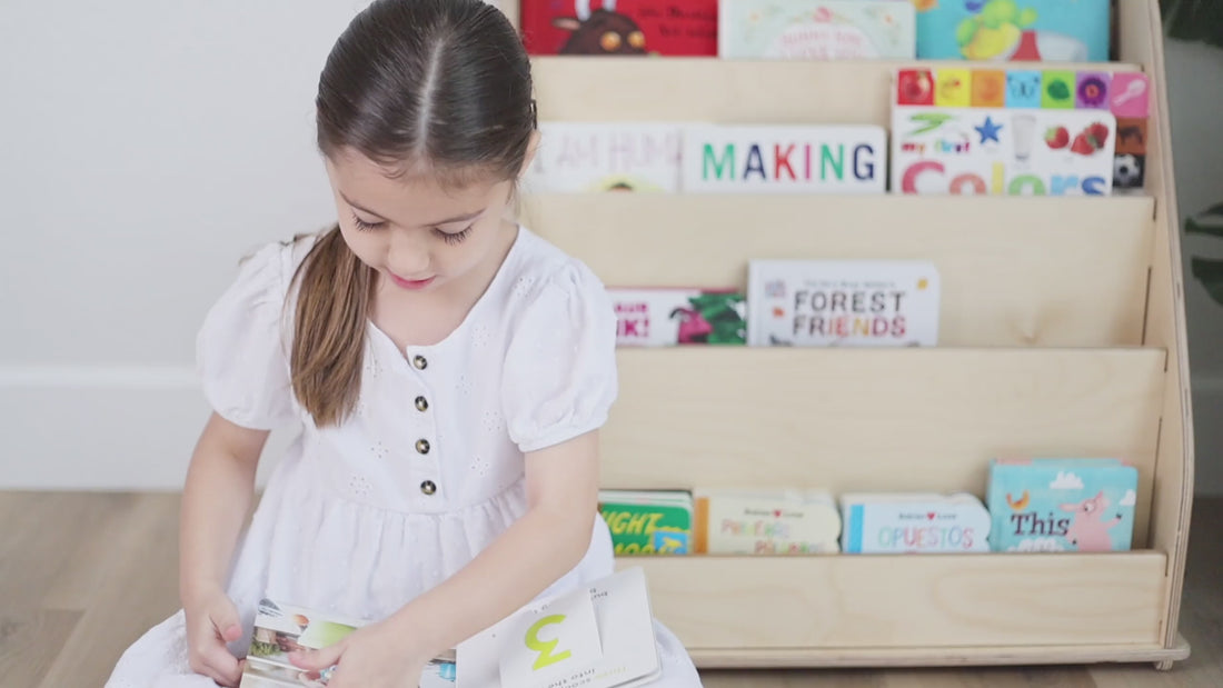 Sofia reading a book in front of the bookshelf