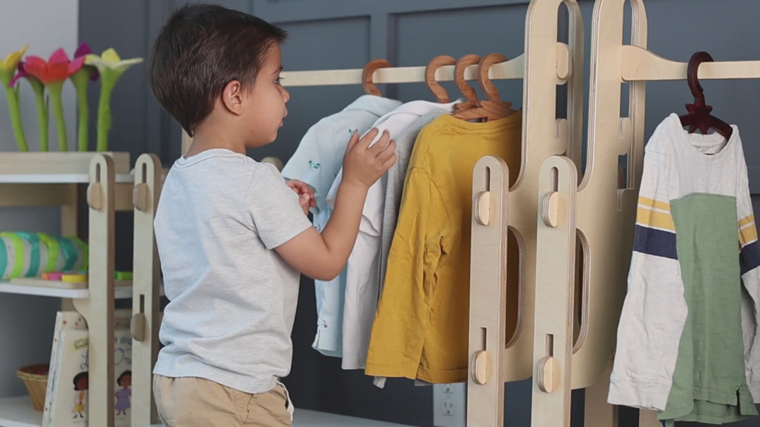 boy picking up his clothes from montessori wardrobe